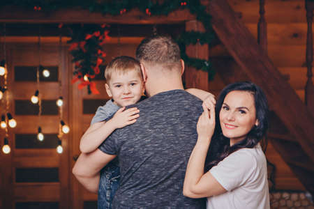 The family celebrates Christmas together. parents with a child among the festive interior. a son in...
