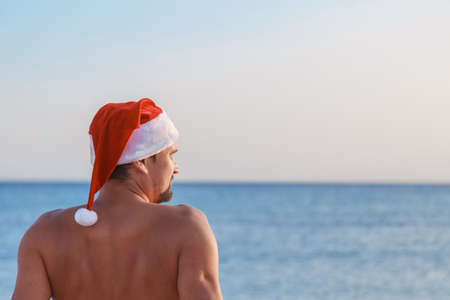 new year's eve on the beach by the sea. a man in a Christmas hat is sunbathing in the sun. blue sky like a copy spaceの写真素材