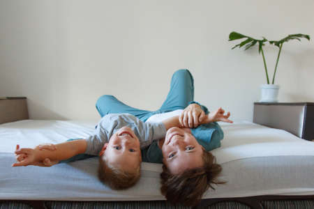 mother's day. mother's love. A happy woman and a boy in blue cloth embrace on the bed. Isolated on a...