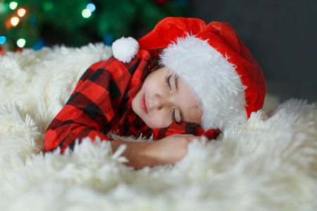 a child in a Santa hat is sleeping New year. the concept of celebrating, enjoying Christmas at midnight. holiday costumeの写真素材