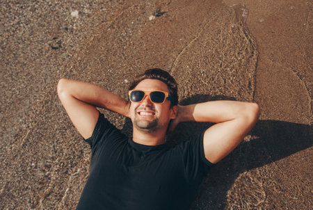 Man on holiday relax in the sun on the deck chair taking off his sunglasses and smilingの写真素材