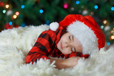 a child in a Santa hat is sleeping New year. the concept of celebrating, enjoying Christmas at midnight. holiday costumeの写真素材