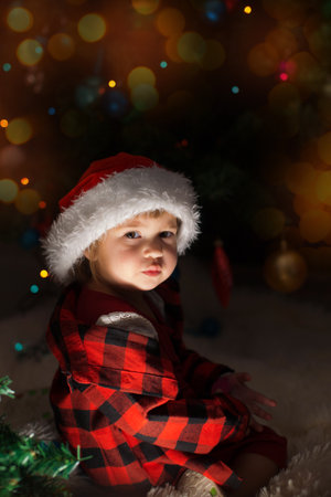 a child in red clothes is sitting waiting for the new year. the concept of celebrating Christmas at midnight. holiday costumeの写真素材