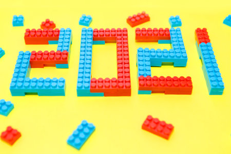 New year, 2021. Lettering from a children's constructor on a yellow background. Toys in isolation....