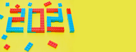 New year, 2021. Lettering from a children's constructor on a yellow background. Toys in isolation. copy space. The concept of a hobby and learning. bannerの写真素材