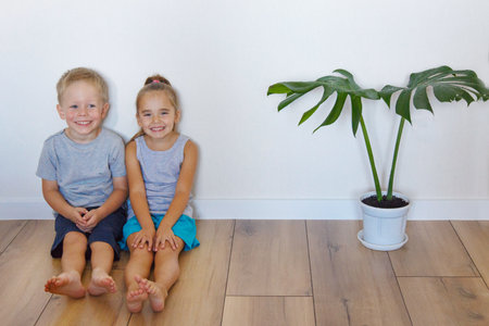 a boy and a girl are sitting on the floor. Children together at homeの写真素材