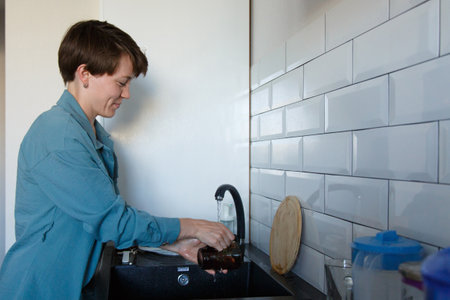 a woman washes dishes. washing the cup in the black sinkの写真素材