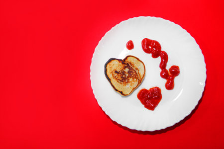 pancakes and ketchup in the shape of a heart on February 14. food for Valentine's day on a red background.の写真素材