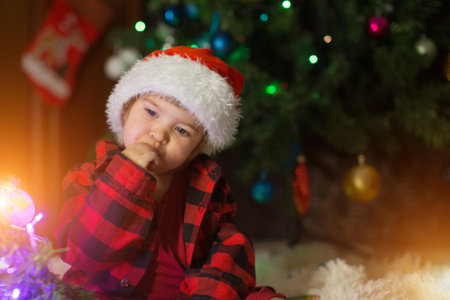 a child in red clothes is sitting waiting for the new year. the concept of celebrating Christmas at midnight. holiday costumeの写真素材