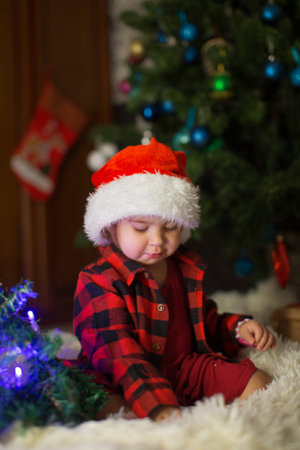 a child in red clothes is sitting waiting for the new year. the concept of celebrating Christmas at midnight. holiday costumeの写真素材