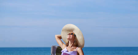 journey to the sea. girl in a bathing suit and hat sunbathing on the beach. tourist sitting on the sand. leisure wear. copy spaceの写真素材