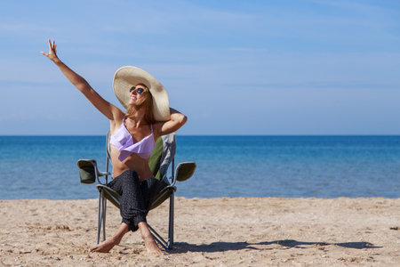 journey to the sea. girl in a bathing suit and hat sunbathing on the beach. tourist sitting on the sand. leisure wear. copy spaceの写真素材