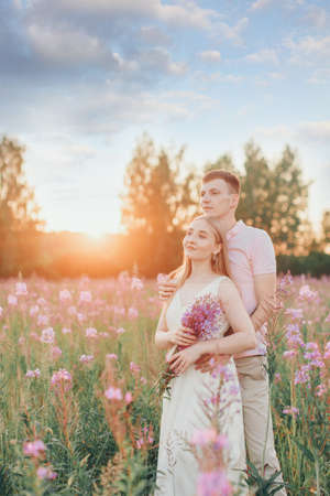 a couple in love walks through a flower meadow. Love and spring blooming. a man embraces a womanの写真素材