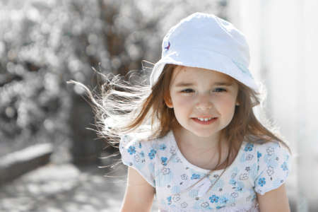 a happy child walks among the white flowers. Love, sunshine, and spring blooming. a girl in a panama hat and a dressの写真素材