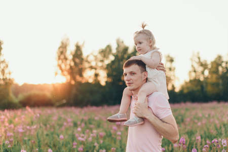 a happy father with daughter walks through a flower meadow. Love and spring blooming. Man and little girl. Father's dayの写真素材