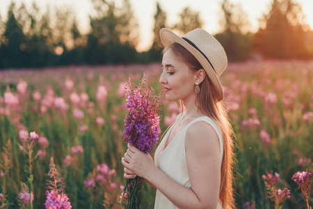 a happy girl with bouquet walks through a flower meadow. Love and spring bloomingの写真素材