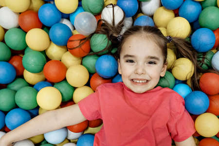 a child in the children's playroom. The girl is having fun among the colorful balls. Dry pool partyの写真素材