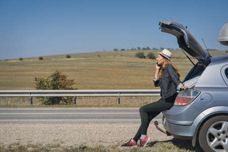 a woman makes a phone call. the tourist stopped on the road. travel by car. calling for car repairs