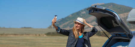a woman makes a phone call. the tourist stopped on the road. travel by car. calling for car repairsの写真素材