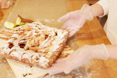 Pie, apples, and cinnamon on a chopping board. The food is ready to eat. Puff pastry