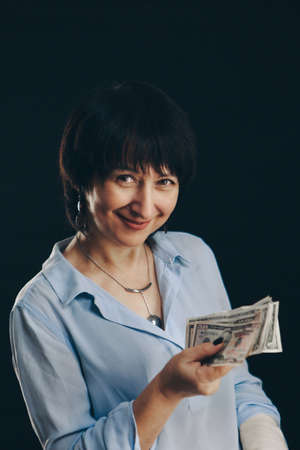 the senora holds the dollars. woman Isolated on a black background. Money at interest, investments,...
