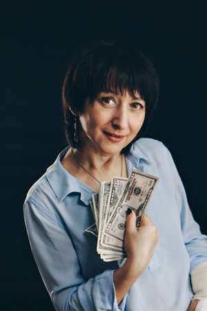 the senora holds the dollars. woman Isolated on a black background. Money at interest, investments, salary. Business and Financeの写真素材