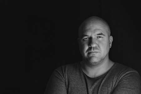 bald handsome man in gray clothes on black backgroundの写真素材
