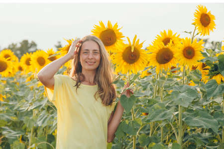a little girl holds a large blooming sunflower. Yellow sunflower petals. A natural background associated with summer. preparing for the harvestの写真素材