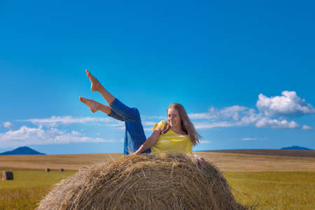 a girl is sunbathing in the hay. village life: harvesting hay for the winter. animal feed.の写真素材