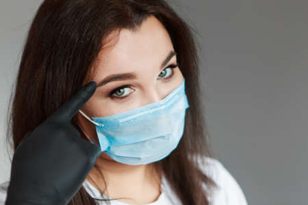 Portrait of a girl who covered her face with a mask. Frightened eyes of the patient. The concept of quarantine, self-isolation, protection from coronavirus, virus, fear of disease, treatment, medicineの写真素材