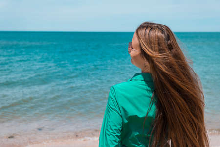 a girl with long hair in a green dress on the beach. beach holidays