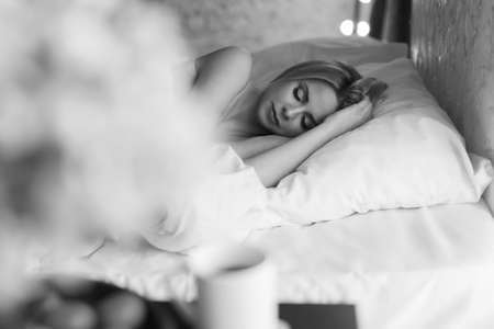 morning girls: a blonde in a blanket sitting on the bed. waking up from a dream. just woke upの写真素材