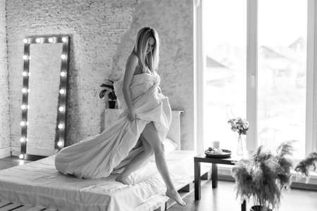 morning girls: a blonde in a blanket sitting on the bed. waking up from a dream. just woke upの写真素材