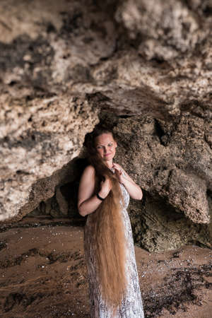 a woman on a rock looking into the distance against the seaの写真素材
