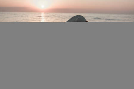journey to the sea. a girl in a dress and hat is walking along the beach. a tourist walks along the sea coast. hot trips during the holiday period. copy spaceの写真素材