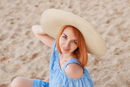 journey to the sea. a girl in a dress and hat is walking along the beach. a tourist walks along the sea coast. hot trips during the holiday period. copy spaceの写真素材