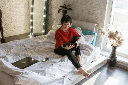 work at home: a girl in bed with a laptop. businesswoman. remote work. shop on the couch. shopping via the internetの写真素材