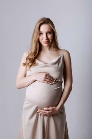 caucasian pregnant woman stroking her belly on white background. Copy space. The concept of healthy digestion, lifestyle, IVFの写真素材