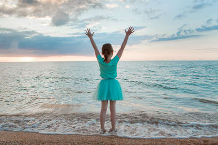 journey to the sea. a girl in a dress and hat is walking along the beach. a tourist walks along the sea coast. hot trips during the holiday period. copy spaceの写真素材