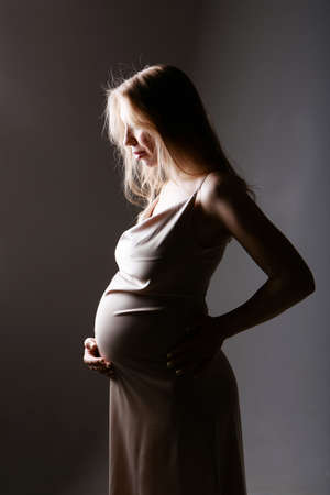 caucasian pregnant woman stroking her belly on white background. Copy space. The concept of healthy digestion, lifestyle, IVFの写真素材