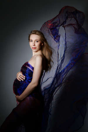 pregnant woman stroking her belly on white background. Copy space. The concept of healthy digestion, lifestyle, IVF. handkerchief like wingsの写真素材