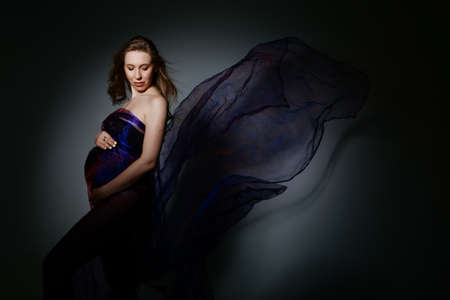 pregnant woman stroking her belly on white background. Copy space. The concept of healthy digestion, lifestyle, IVF. handkerchief like wingsの写真素材