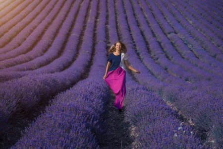 a girl in a dress on a lavender field. the woman runs. A handkerchief like wingsの写真素材