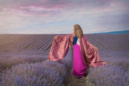 a girl in a dress on a lavender field. the woman runs. A handkerchief like wingsの写真素材