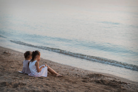 Two European girls enjoy the sunset on the sea, play, hug, smile. Love sisters on the beach. as a gift from daughters mother's day. Family vacation at the hotel. Happy childhood in summer. High quality photo.の写真素材
