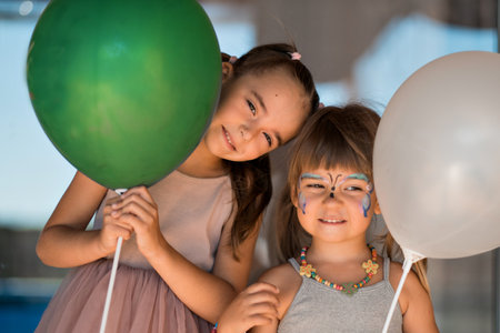 Two little sisters with face painting smile with balloons. Childrens holiday, happy children. Girls birthday. High quality photo.の写真素材