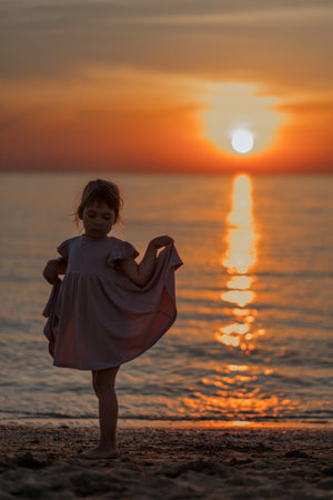 girl playing on the beach at sunset. Family holiday. High quality photo.の写真素材