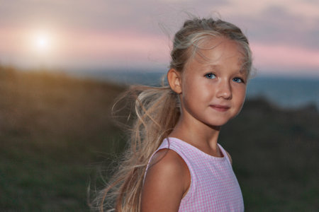 Happy girl smiling in the evening on the beach at sunset. A tanned blonde in a pink light dress is enjoying her vacation. High quality photoの写真素材
