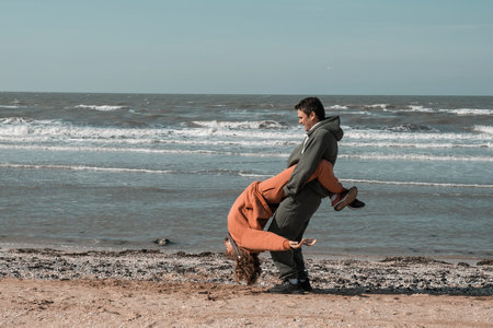 The guy and the girl hug and look at each other with love on the beach, against the backdrop of the...
