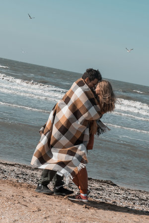 The guy and the girl hug and look at each other with love on the beach, against the backdrop of the Blue Sea. Tender relationship of husband and wife. The date of the young couple on Valentine's Day. High quality photoの写真素材